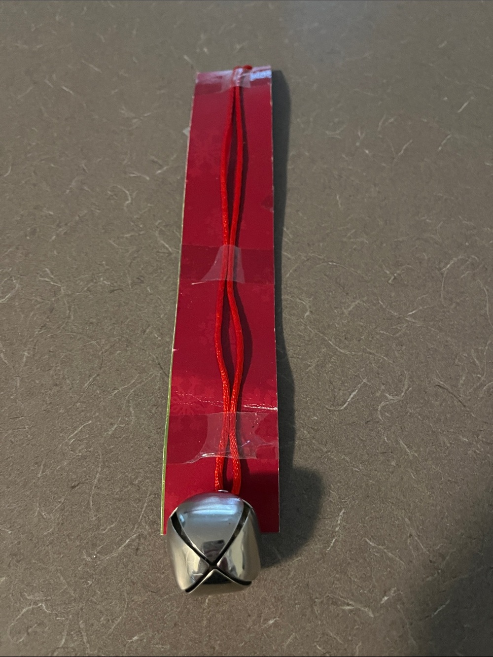 Jingle bell in silvertone with red cord. 2.5” ball